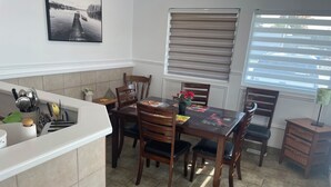 Una cocina con mesa, sillas, una ventana con persianas y zona de fregadero.