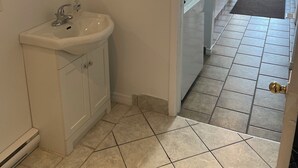 Un baño con lavamanos, espejo y argollas para toallas.