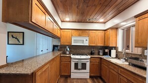 A kitchen with wooden cabinets, a granite countertop, a white stove, and a microwave. - Good Vibes getaway lake views, Marina, private Boat Slip (Bass Lake)