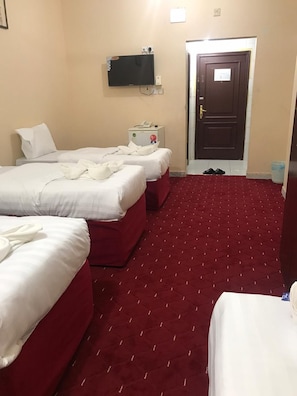 Habitación de hotel con dos camas, un televisor, una puerta y una alfombra roja.