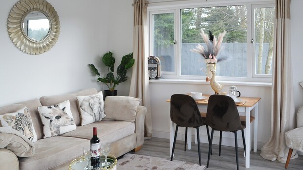 A living room with a sofa, a coffee table, and a dining area with chairs and a table. - Old Colliery Cottage (Shilbottle, near Alnwick)