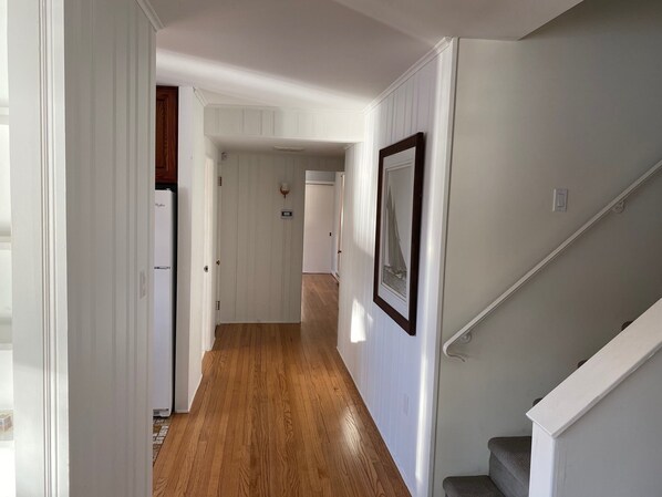 A hallway with wooden flooring, white walls, and a staircase. - Lakefront Home in Lake Winola, PA (Factoryville)