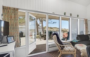A room with a large sliding glass door leading to an outdoor area with a table and chairs. There is a wicker chair and a sofa inside the room. - Beautiful home in Pandrup with WiFi (Pandrup)