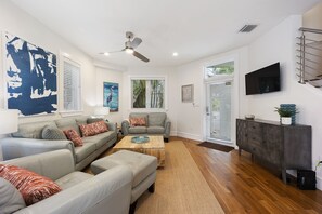 A spacious living room with a grey sofa set, a wooden coffee table, and a grey armchair.