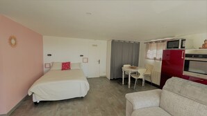 A hotel room with a bed, a small dining table with chairs, a microwave, and a red refrigerator. - Bas de villa near Calanques de Cassis in quiet subdivision (Carnoux-en-Provence)
