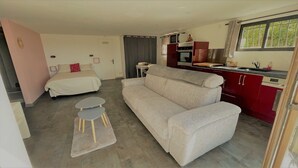 A compact living space with a sofa, a small table, a bed, and a kitchenette. - Bas de villa near Calanques de Cassis in quiet subdivision (Carnoux-en-Provence)