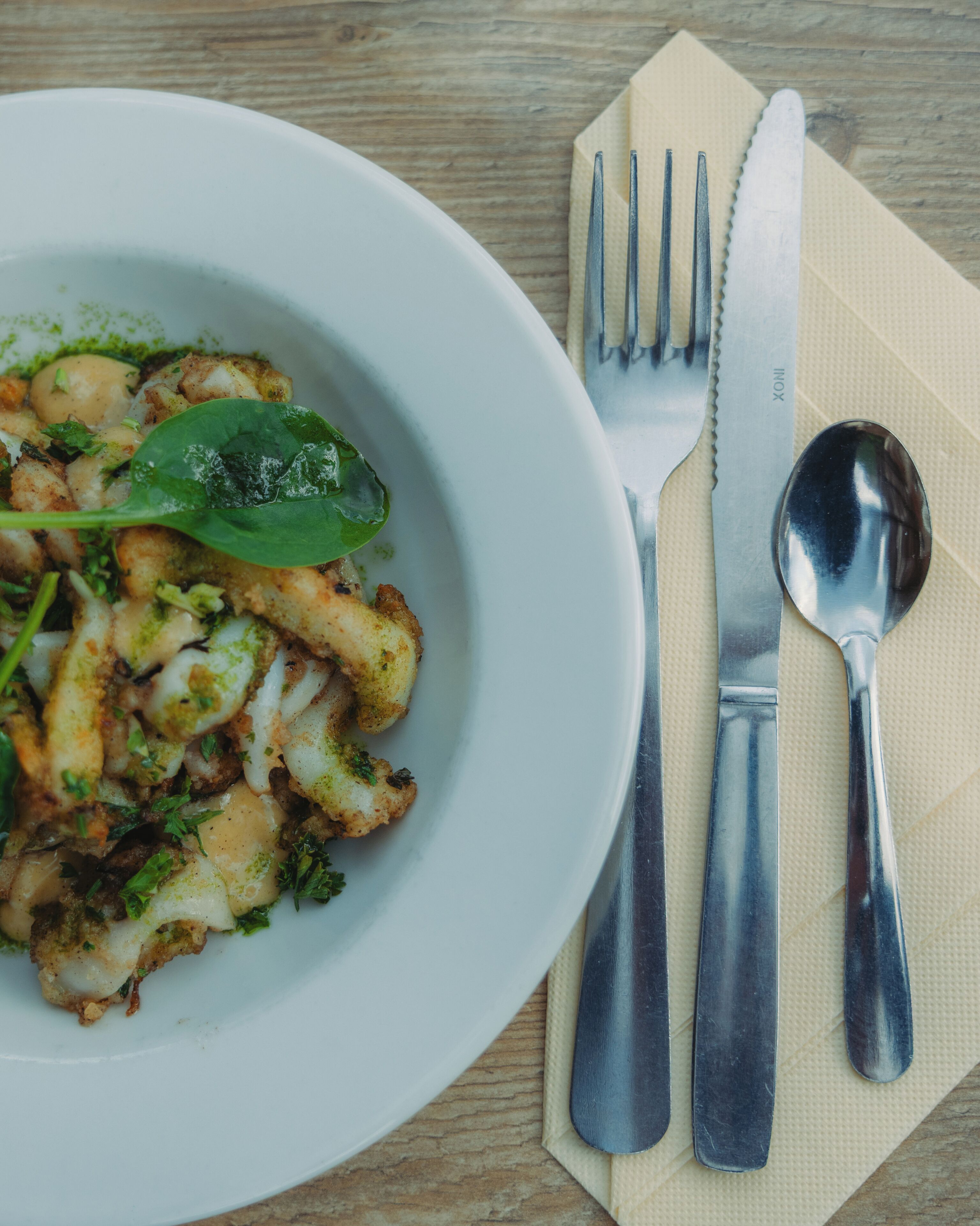 A plate of food with a fork and spoon on a napkin.