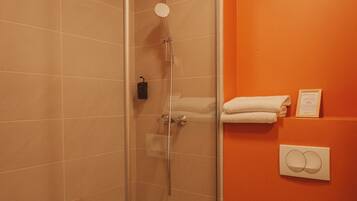 A bathroom with a glass-enclosed shower, a toilet, and a towel rack.