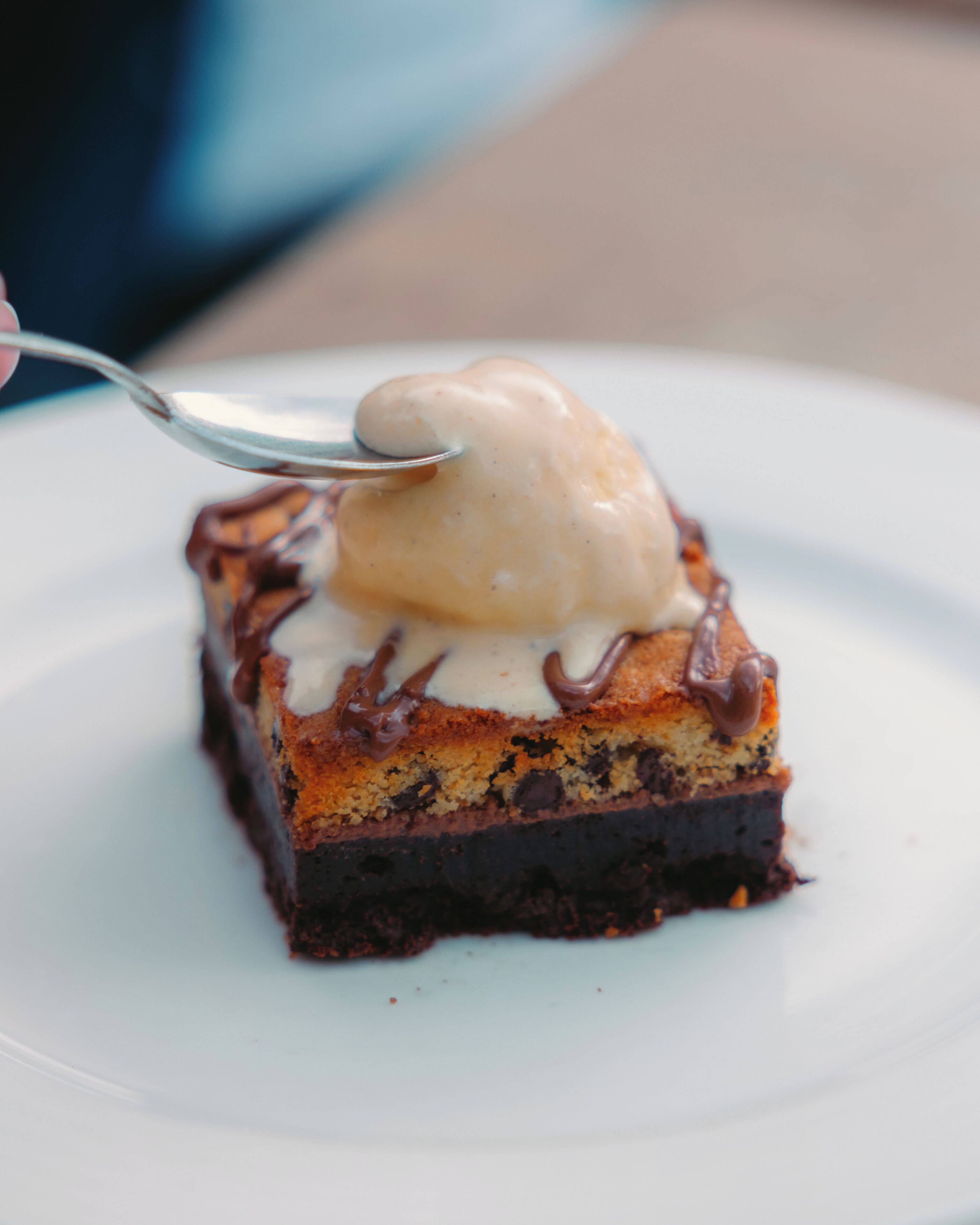 Una porción de postre con una bola de helado encima, servida en un plato blanco.