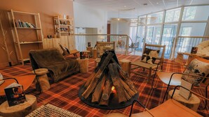 Una habitación acogedora con chimenea, muebles de madera y ventanas amplias.
