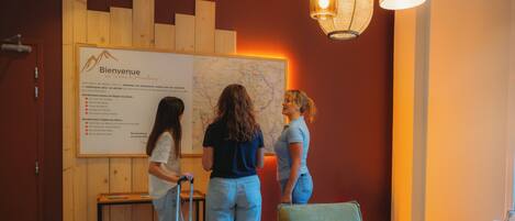 A reception area with a wooden wall, a map, and a seating area with a green sofa and a small table.
