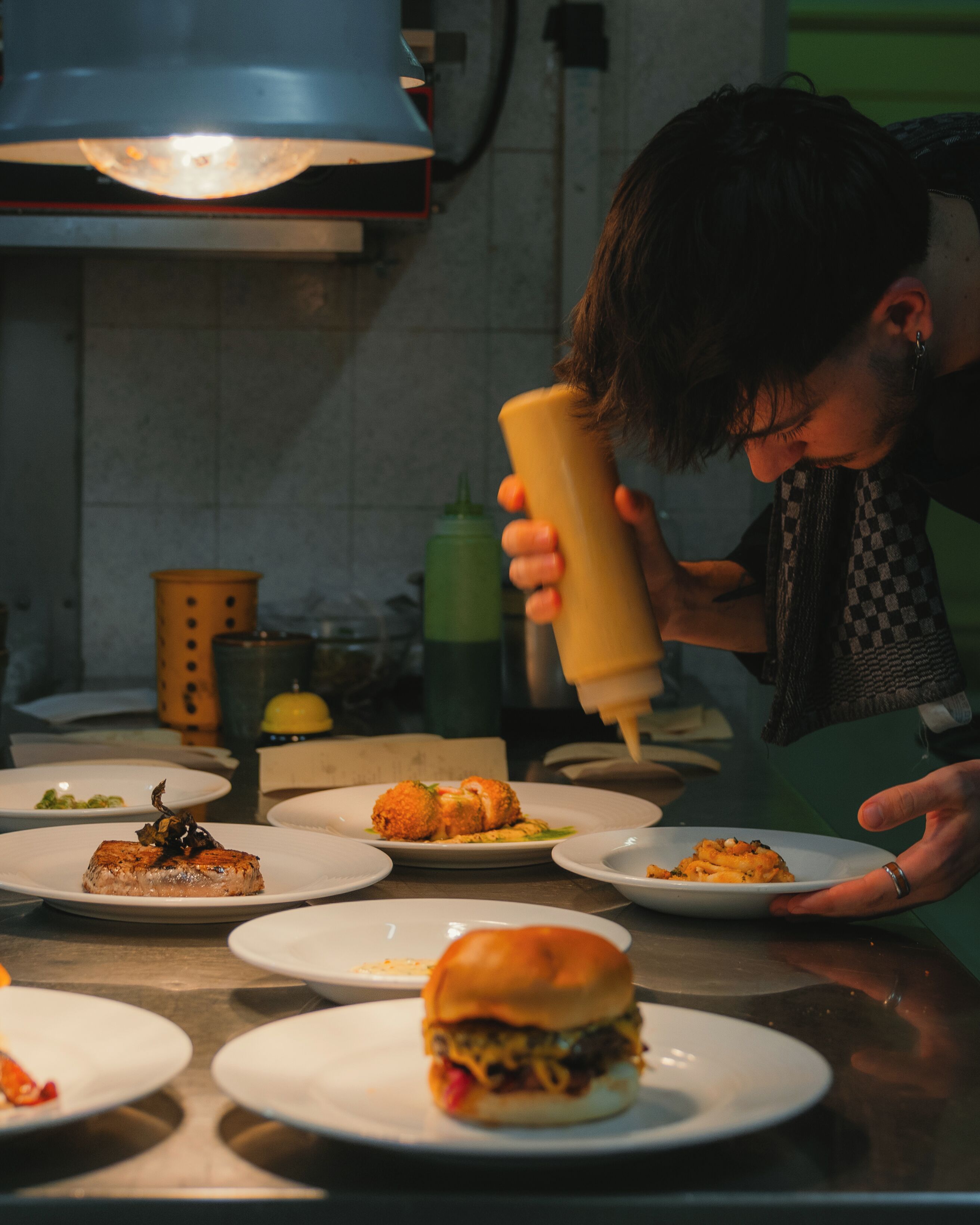 A person preparing food in a kitchen with various dishes on the counter.