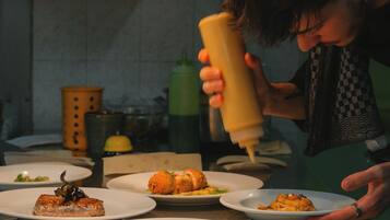 A person preparing food in a kitchen with various dishes on the counter.