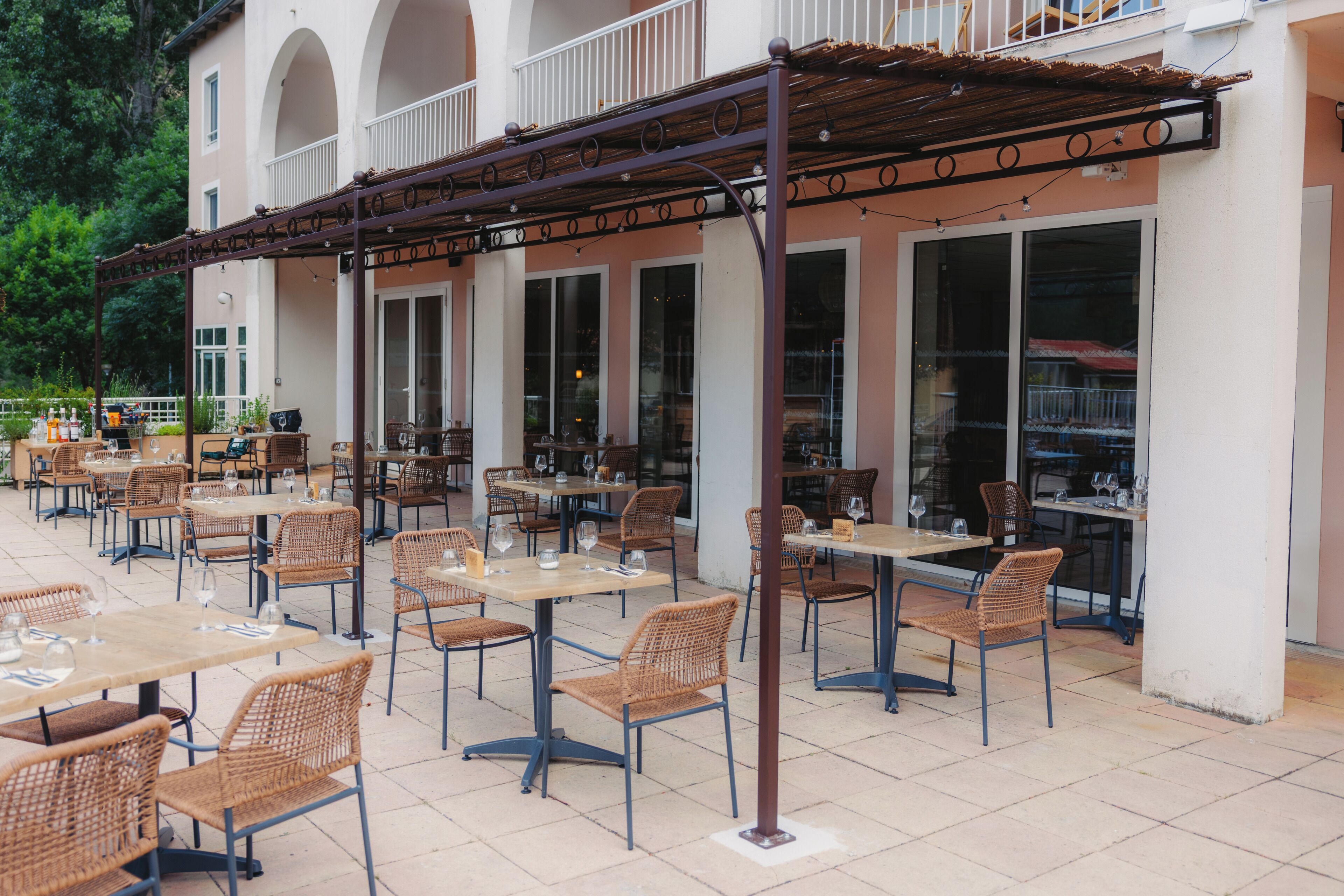Ein Straßencafé mit Korbmöbeln und Glastüren.