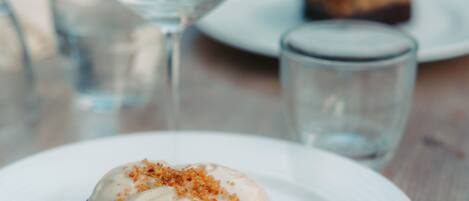 A dessert on a white plate with a glass of water and a glass in the background.