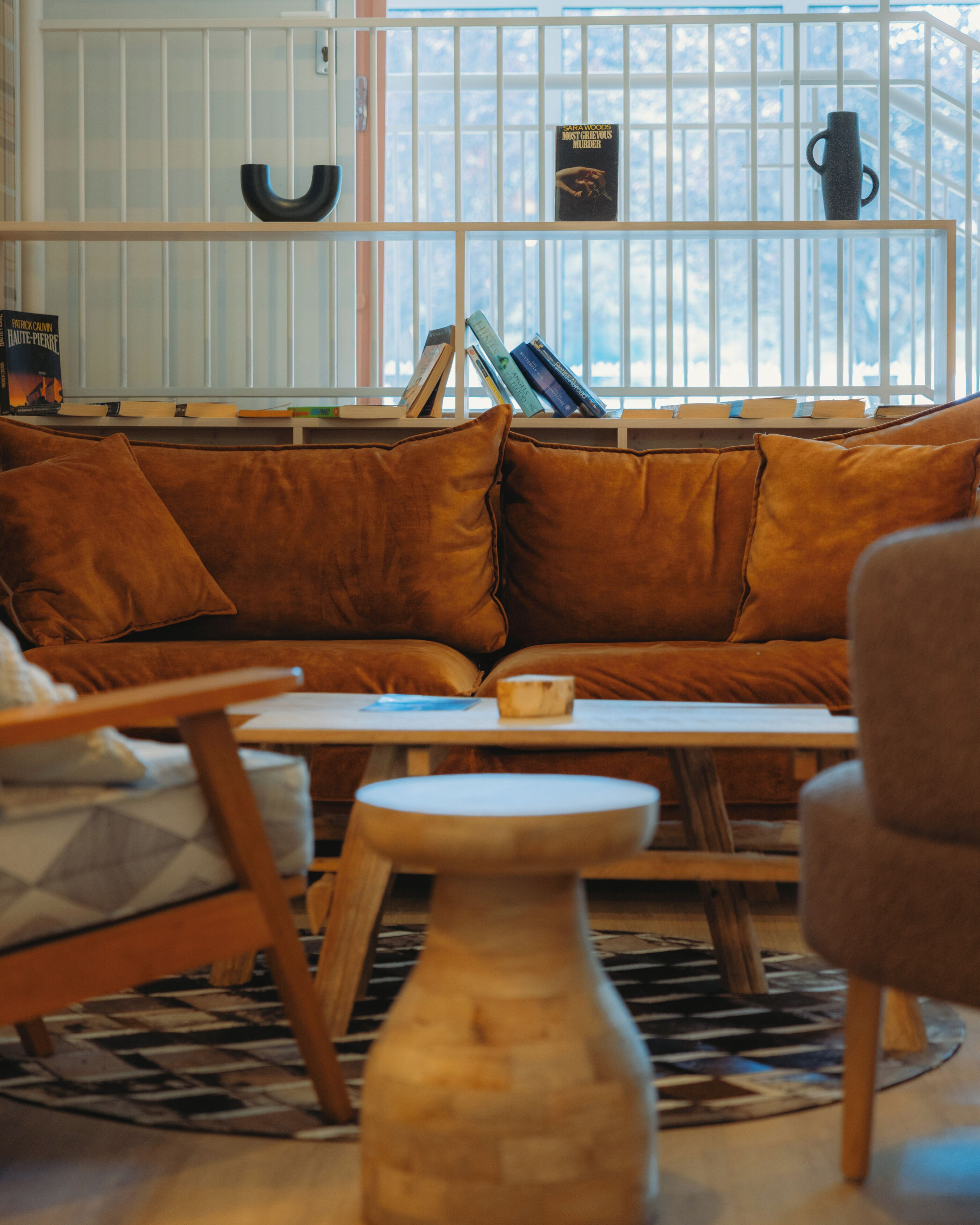 A cozy living room with a sofa, a coffee table, and a bookshelf against a window with blinds.