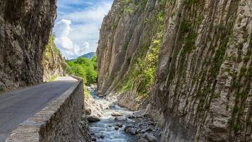 A narrow road flanked by steep rock walls with a river running through the center.