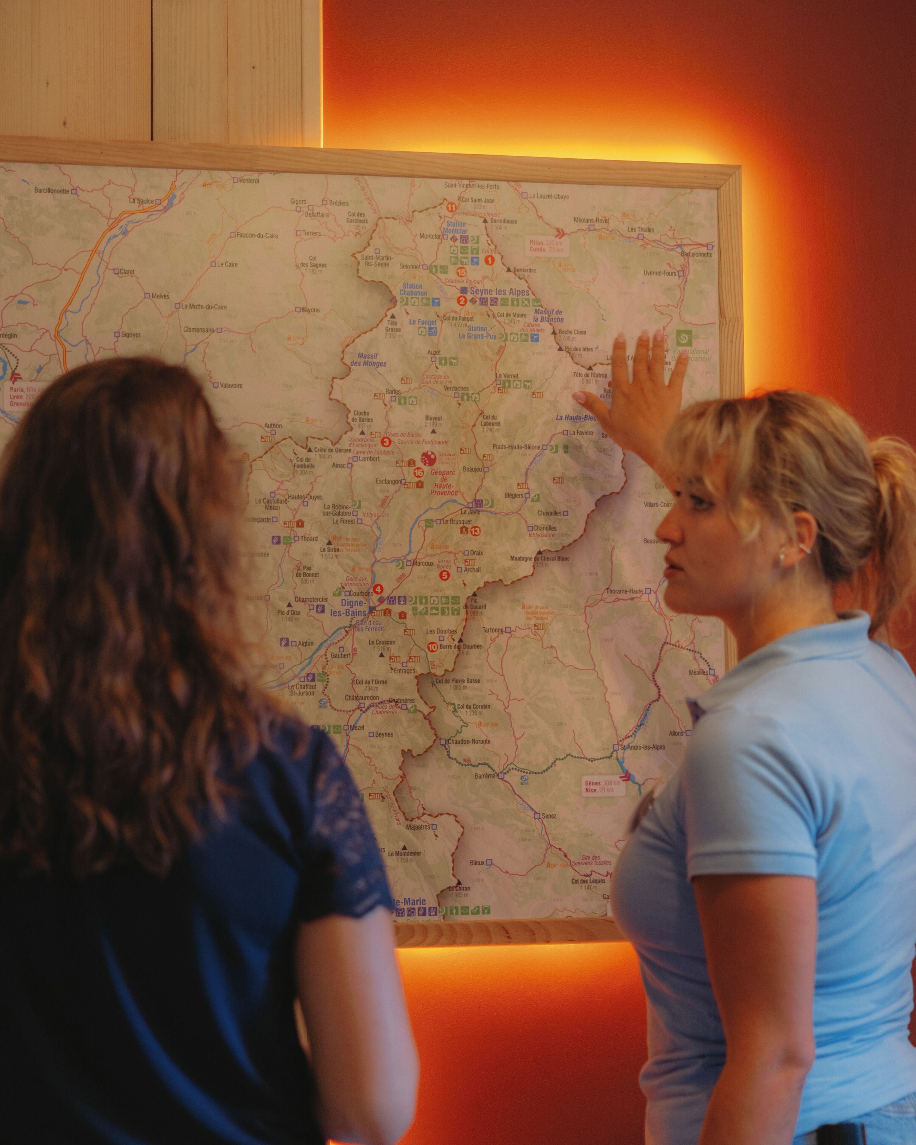 Two individuals examining a large map with various marked locations and routes.
