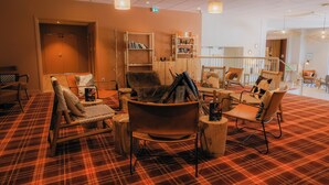 Un espacio lounge acogedor con alfombra escocesa, mobiliario de madera y chimenea.