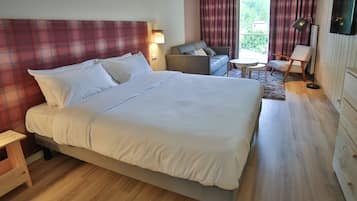 A hotel room with a large bed, a sofa, a small table, and a TV.