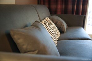 Un sofá gris con dos almohadones, uno a rayas y otro liso.