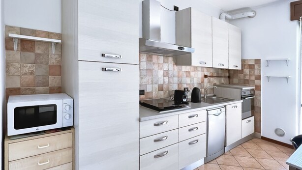 Una cocina moderna con armarios blancos, un microondas, una estufa y un lavamanos.