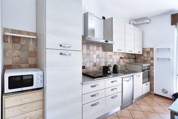 A modern kitchen with white cabinets, a microwave, a stove, and a sink.
