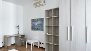Un dormitorio con cama, escritorio, silla, armario y un cuadro en la pared.
