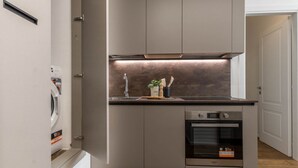 Una cocina compacta con horno integrado, pileta de acero inoxidable y un salpicadero moderno.