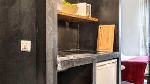 A kitchenette with a toaster, a basket, and a wooden cutting board. - Hosmate - Milano - Sammartini's Cave - Stazione Centrale (Milano)