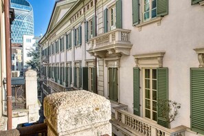 A narrow street with historic buildings, a stone balustrade, and a modern glass building in the background.