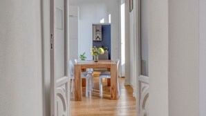 Un corridoio che conduce a una sala da pranzo con un tavolo di legno e sedie bianche.