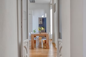 A hallway leading to a dining area with a wooden table and white chairs.