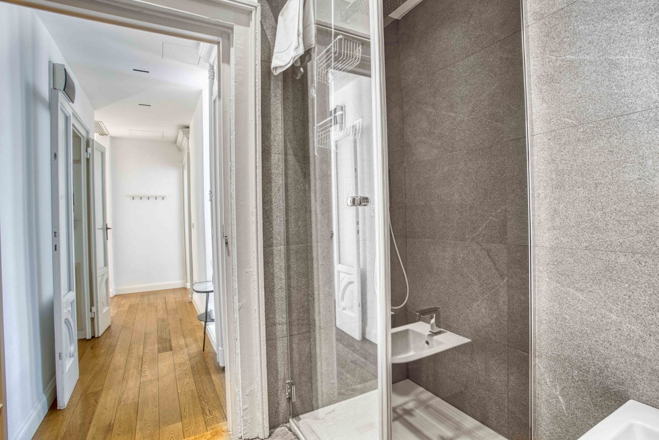 A modern bathroom with a glass shower enclosure, a pedestal sink, and a walk-in shower.