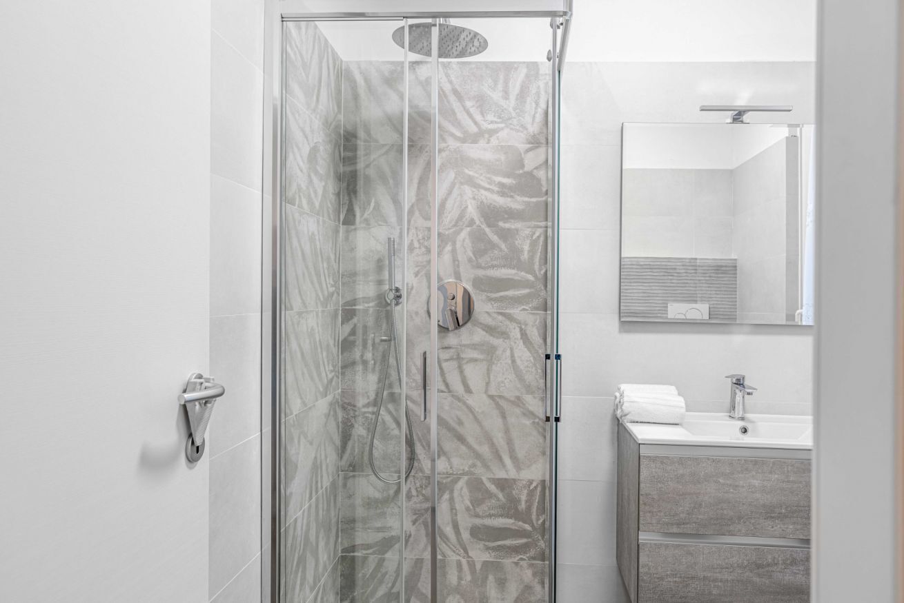 Une salle de bain moderne avec une douche à parois de verre, un lavabo avec un miroir et un porte-serviettes.