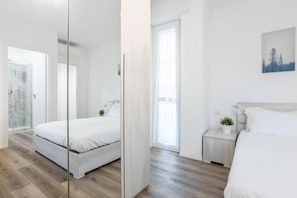Um quarto moderno com cama, mesa de cabeceira e janela.