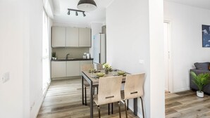 Een moderne keuken met witte kasten, een eettafel met stoelen en een hanglamp.