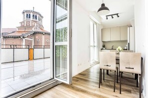 A modern kitchen with a dining area, large windows, and a view of a historic building. - Hostamte- Milano - Varanini - NoLo (Milano)