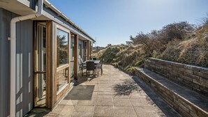 Ein modernes Gebäude mit großen Fenstern und einer Terrasse mit Außenbestuhlung.
