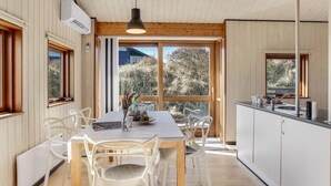 Eine moderne Küche mit Holzboden, weißen Schränken und einem Essbereich mit Tisch und Stühlen.