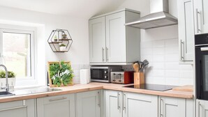 A modern kitchen with white cabinets, a built-in oven, a microwave, and a toaster. - 2 bedroom accommodation in Corwen (Corwen)
