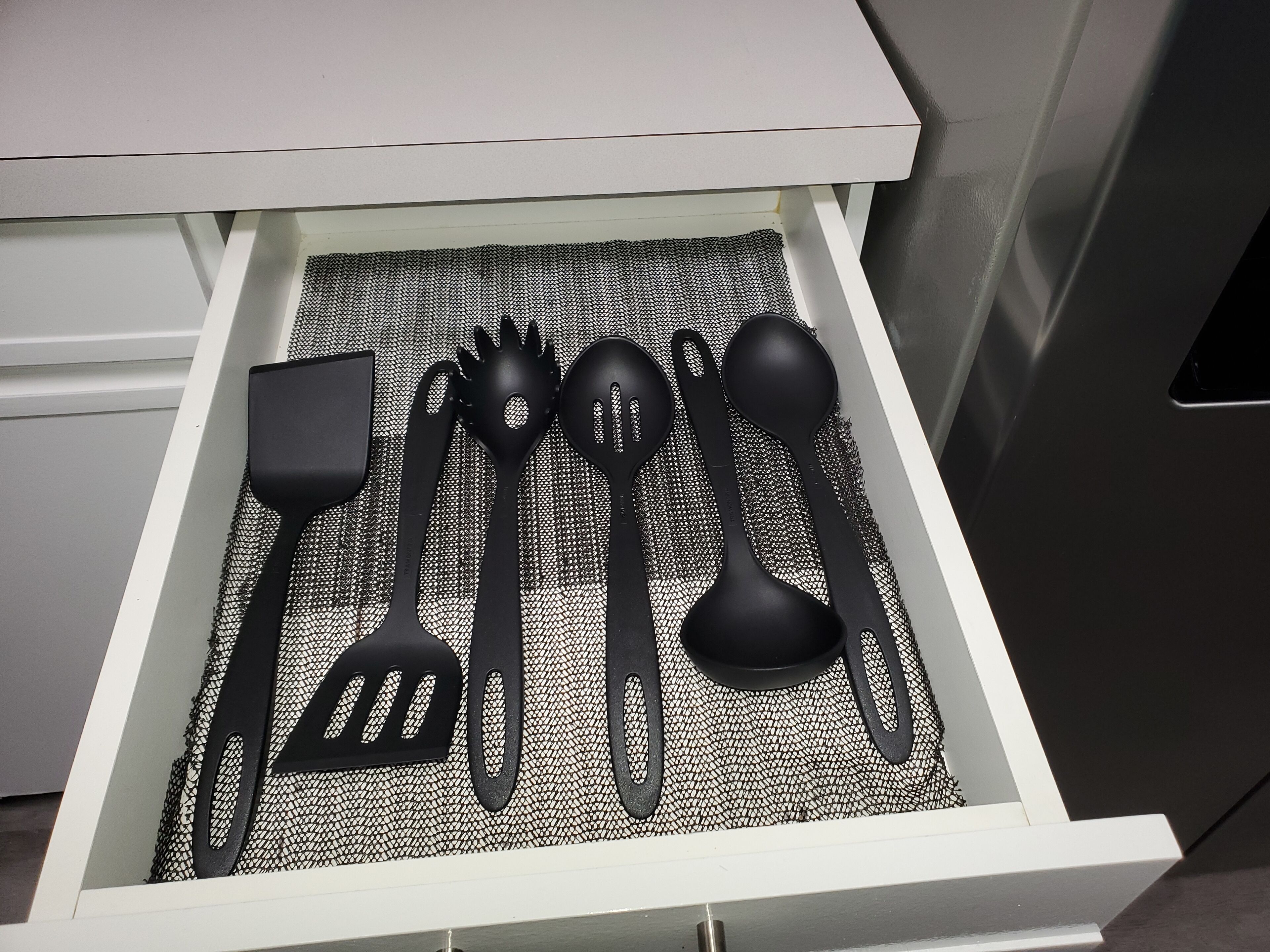 Eine Schublade mit schwarzen Küchenutensilien.