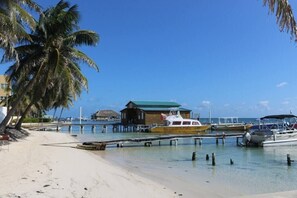 A beach with a wooden structure, boats, and a clear blue sky.