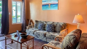Une pièce comprenant un canapé, une table, une lampe et un tableau accroché au mur.