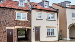 A two-story building with a brick facade and a white upper level. There is a sign indicating 'Old Smoke House Cottages' and a 'No Smoking' sign. - Nans Cottage - UK43350 (Whitby)