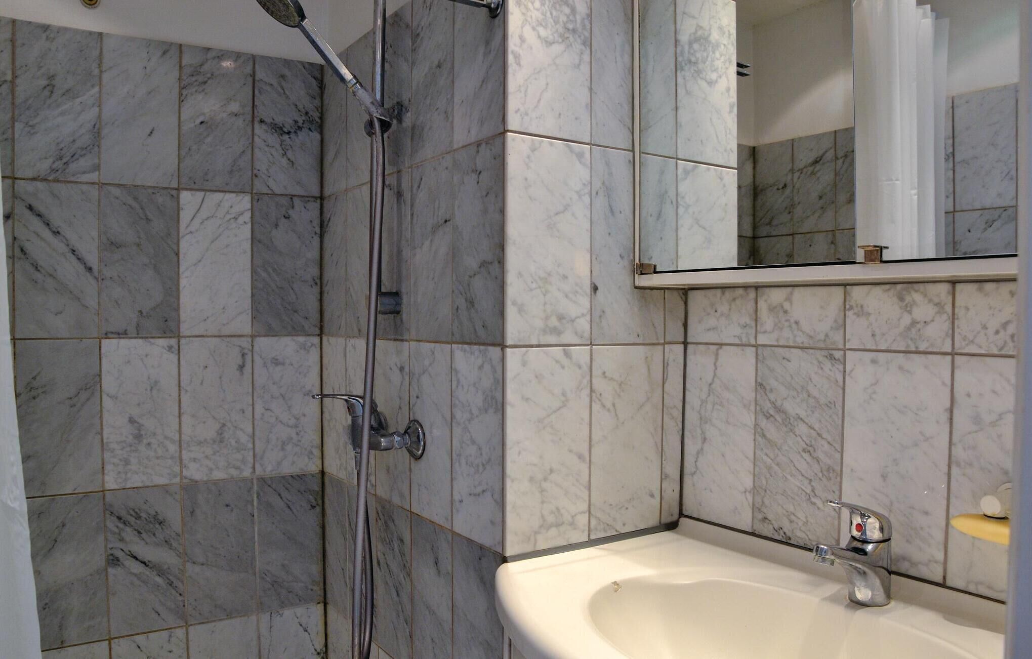 A bathroom with a shower, a sink, and a mirror.