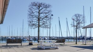 A marina with boats docked, benches, and a clear sky.