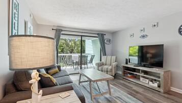 Ein Wohnzimmer mit Sofa, Couchtisch, TV-Schrank und einer Lampe.