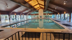 An indoor swimming pool with a wooden ceiling and large windows.