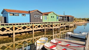 Un muelle de madera con edificios de madera de colores, una masa de agua tranquila y barcos amarrados.
